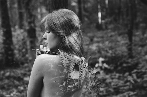 Monochrome Photo of a Topless Woman Holding Fern Leaves