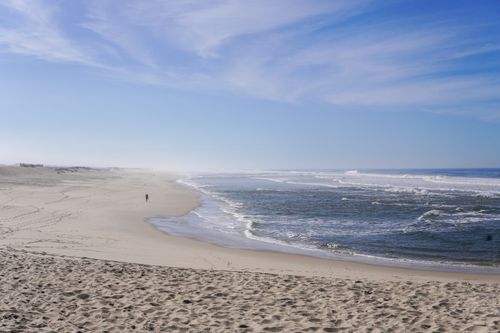 Free A tranquil beach scene featuring sandy shores and gentle waves under a clear blue sky. Stock Photo