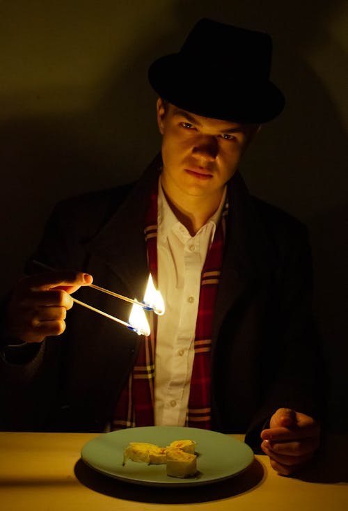 A Man in Black Suit Holding a Lighted Sticks