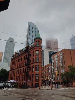 Historical Gooderham Building amidst Toronto's modern skyline under cloudy skies.