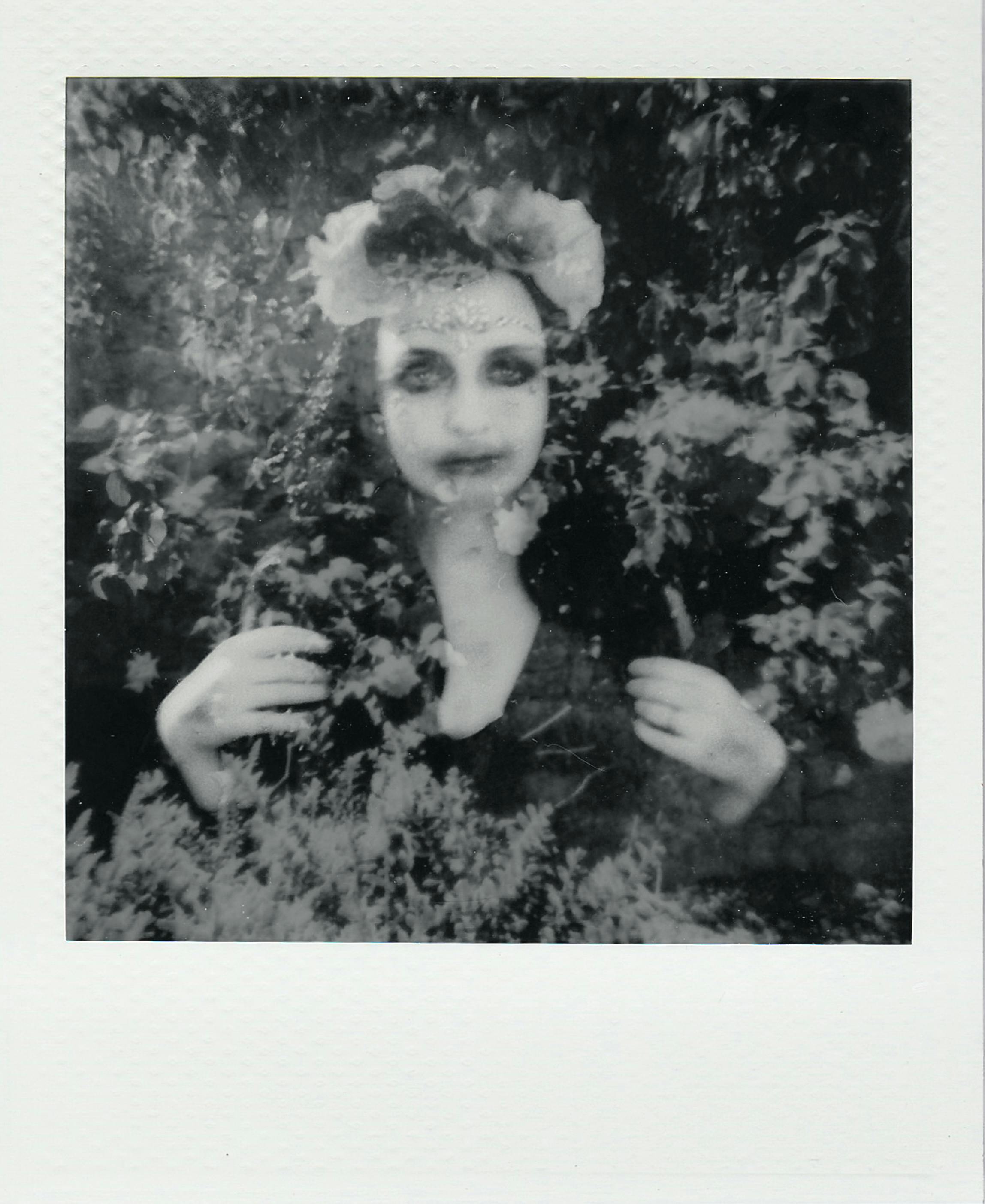 Monochrome double exposure portrait of a woman blended with floral textures, creating a mysterious effect.