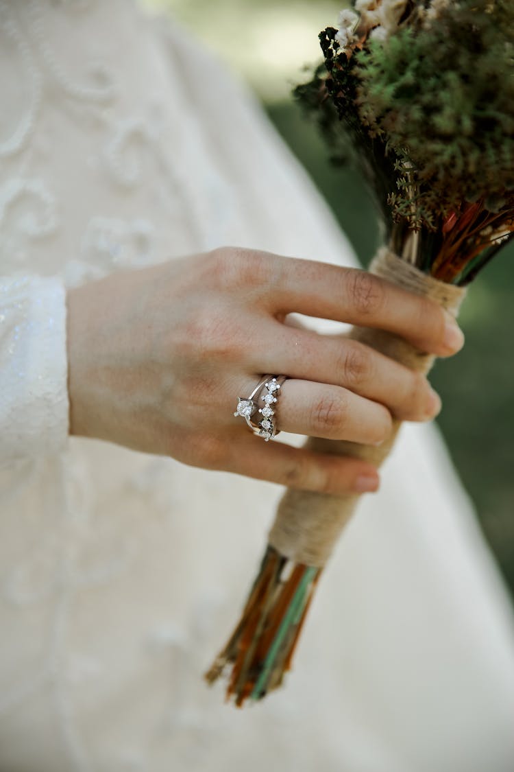 Close Up On Womans Hand In Wedding Clothes Holding Flowers