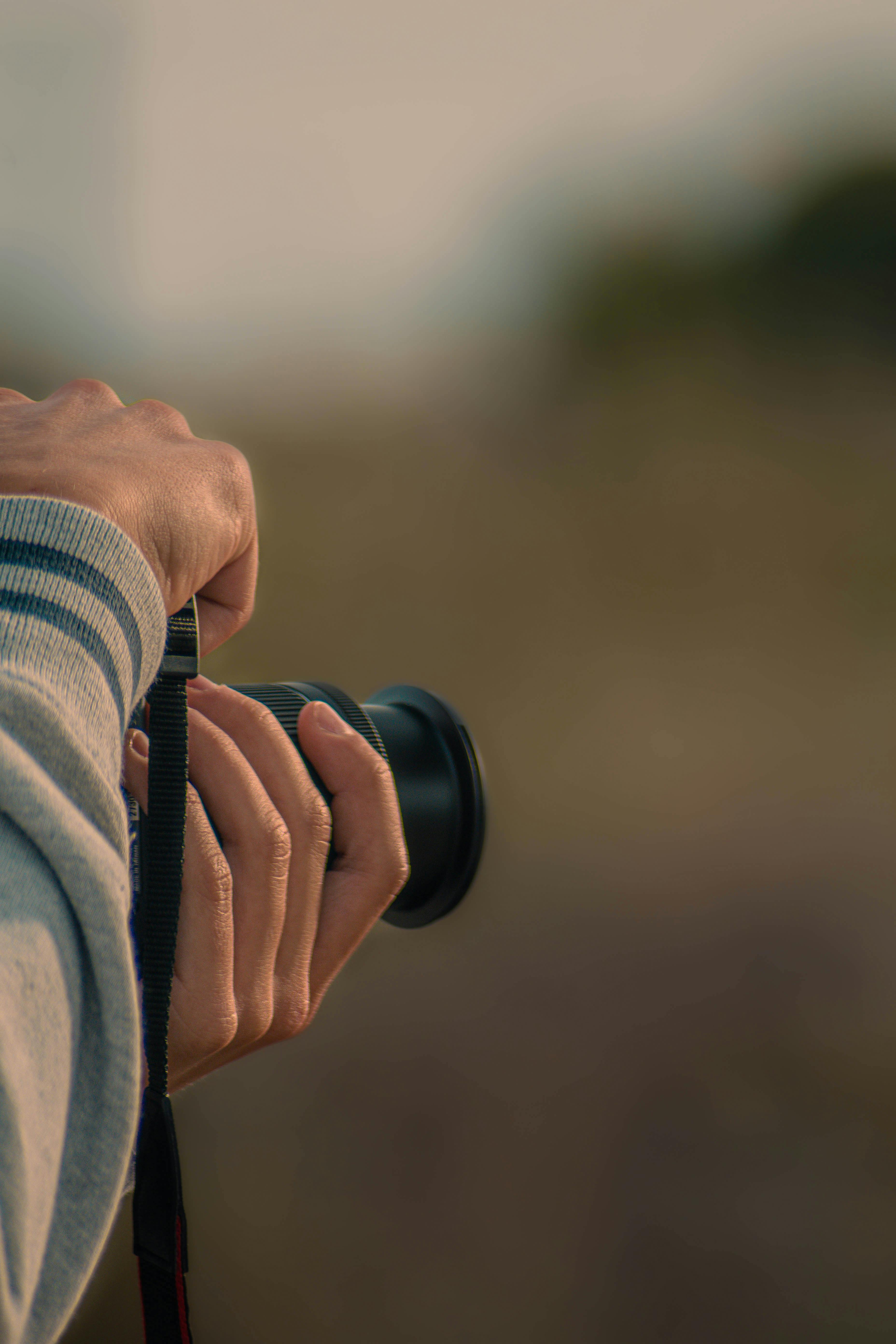 Free Close-up of hands holding a camera outdoors in Castelo Branco, Portugal. Stock Photo