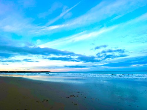 Free Peaceful beach scene with blue skies at Filey, England during sunrise. Stock Photo