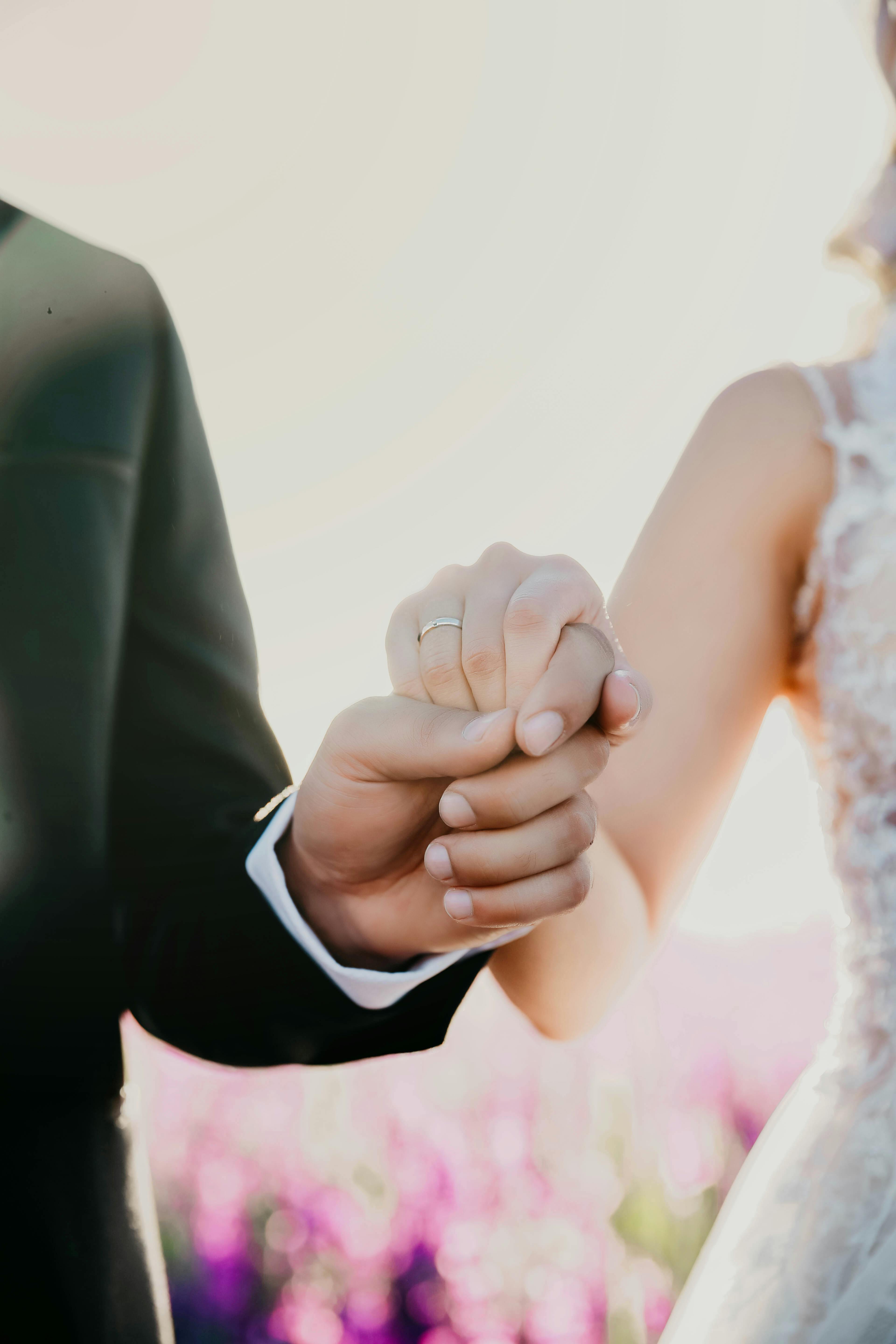 close up on man holding womans hand in wedding clothes