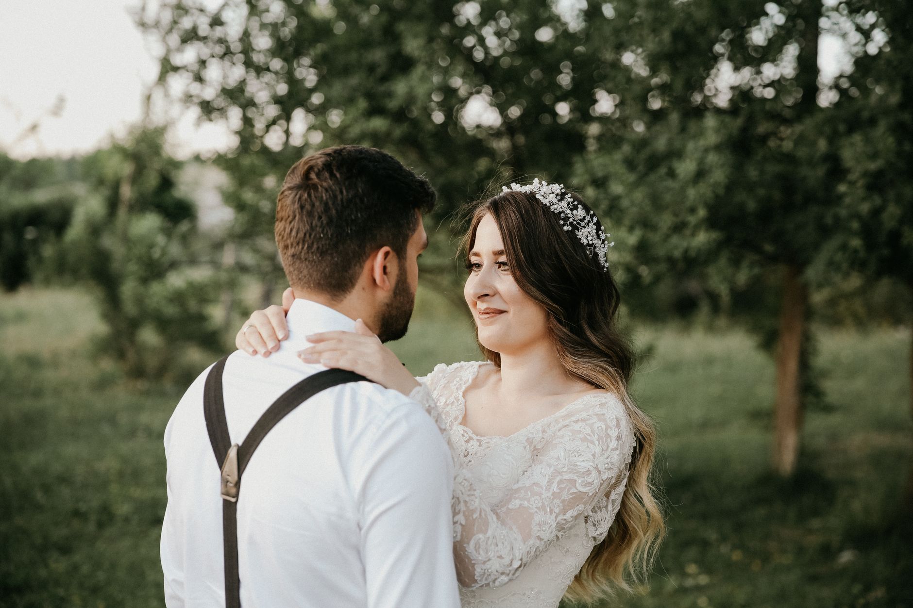 styled flat lay on a cream linen surface showing wedding hair accessories - a pearl cluster hair comb, two crystal-tipped pins, a short birdcage veil on its comb, dried lavender sprigs, and a folded i