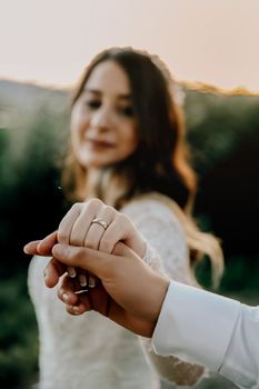 Close-up of newlyweds holding hands, focusing on wedding ring and love.