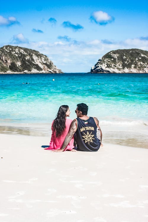 Free A Couple Sitting on the Beach Sand while Having Conversation Stock Photo
