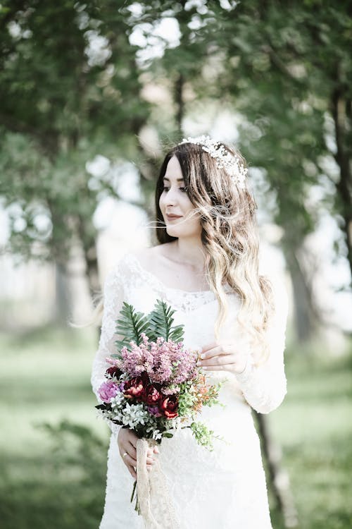 A Beautiful Bride in White Wedding Gown Holding a Bouquet of Flowers