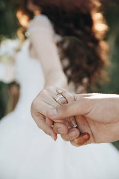 Close-up of a bride and groom holding hands symbolizing love and unity.