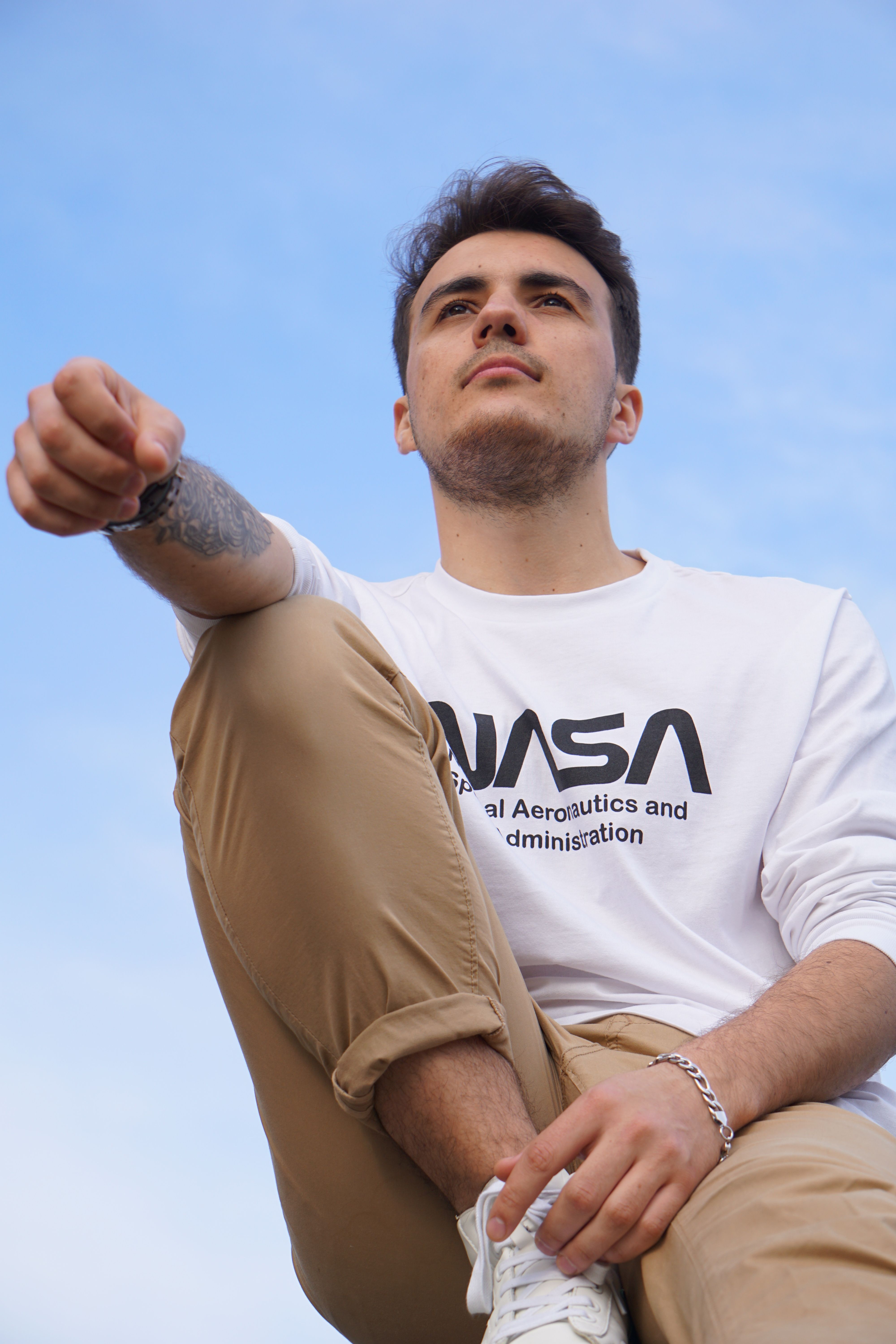 Young man in brown pants and white shirt gazes upwards, inspiring confidence.