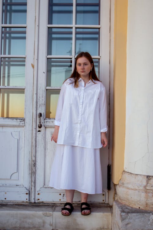 Girl in White Shirt and Skirt next to Door