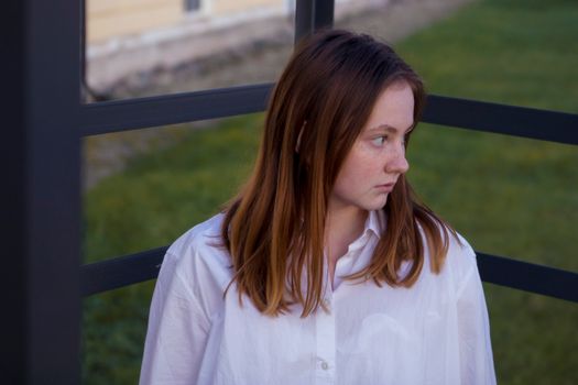 Young woman with long brown hair looking to the side in an outdoor setting.