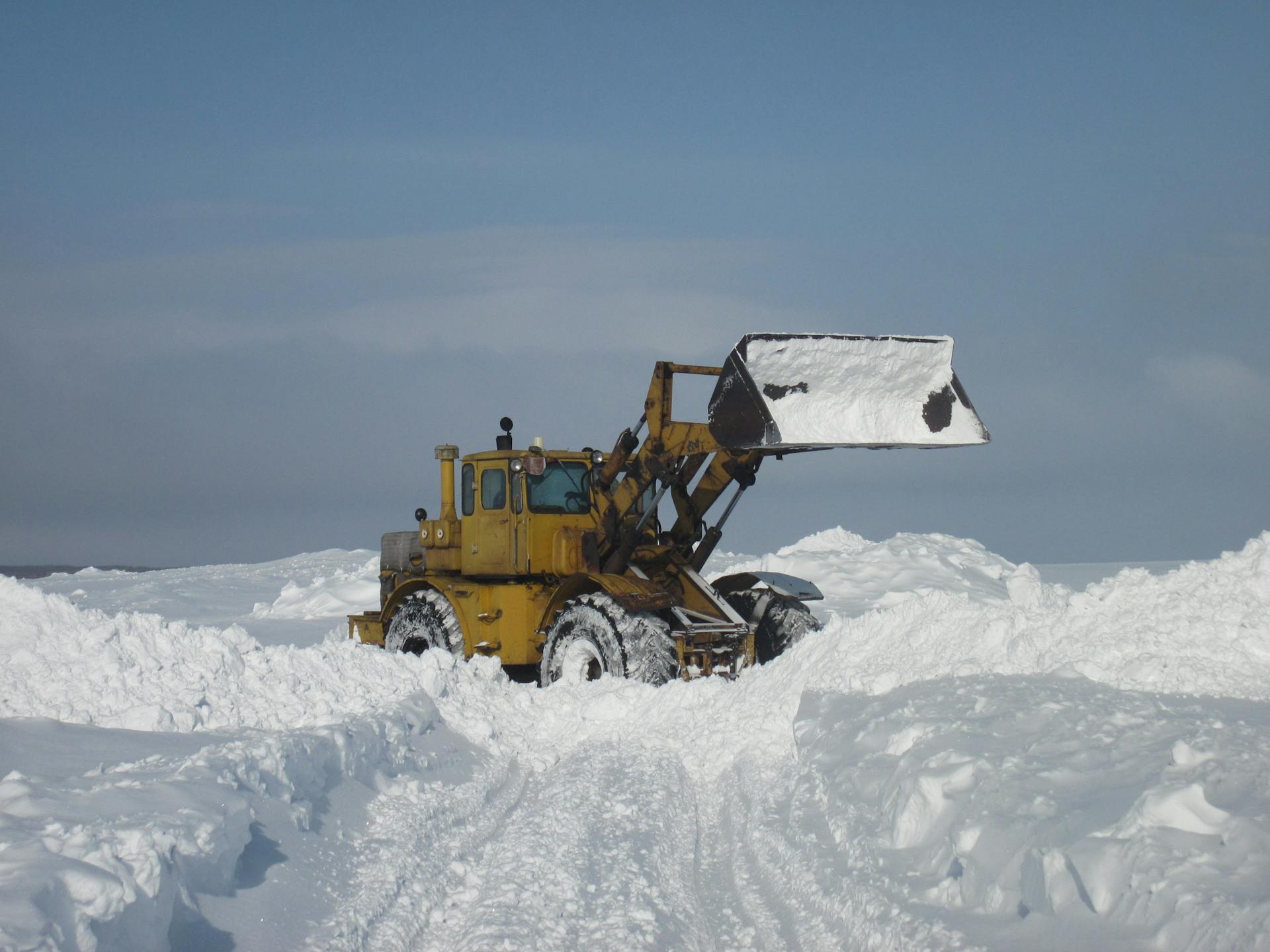 A bulldozer pushes through heavy snow in a winter landscape in Saratov, Russia.