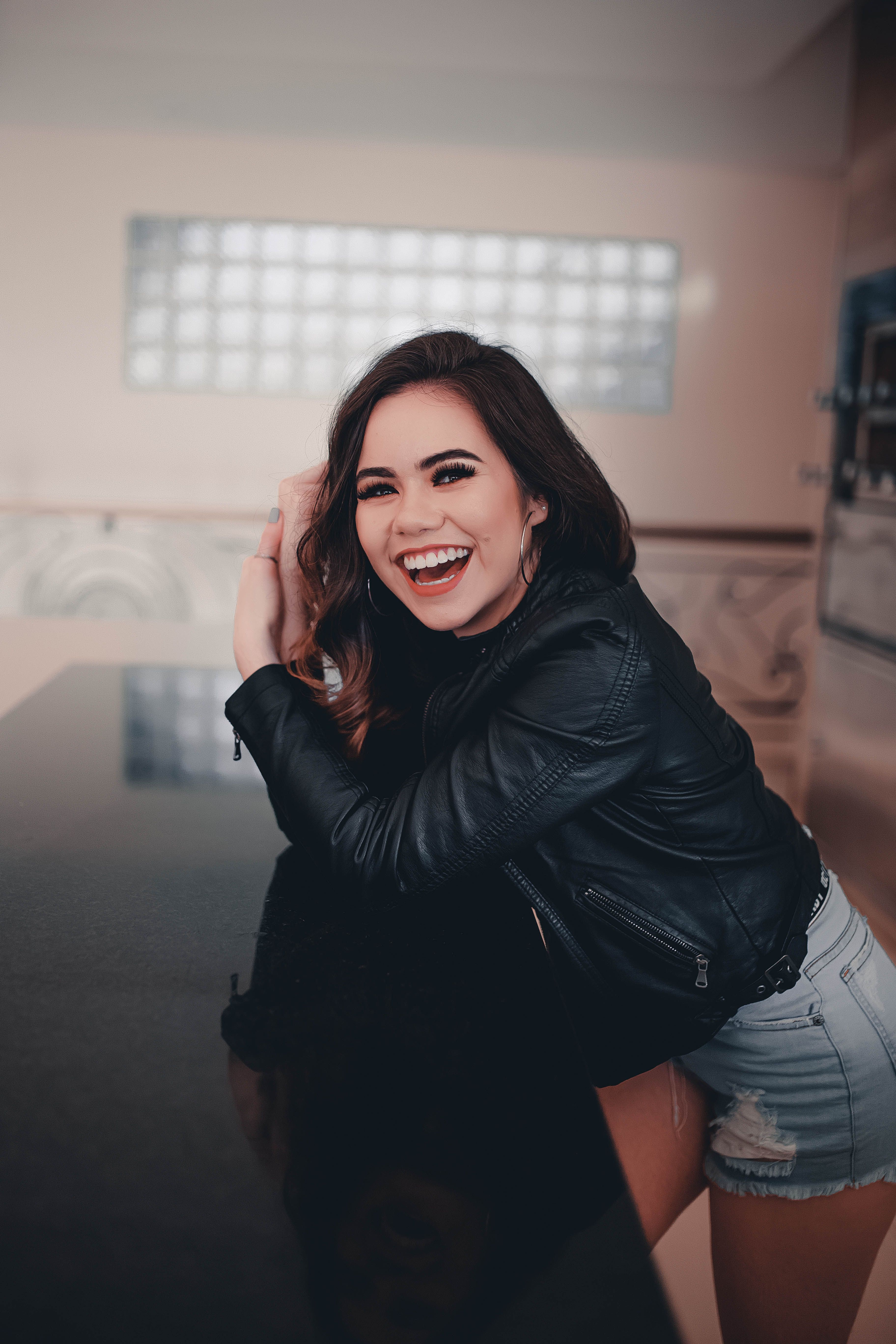 A Woman in Black Leather Jacket and Denim Shorts Smiling while Standing ...