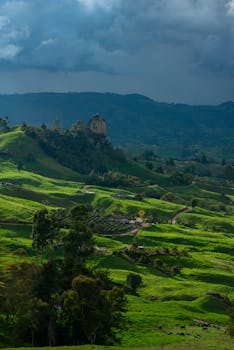 Lush green rolling hills with a dramatic sky, showcasing a serene countryside landscape.