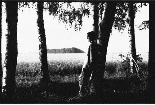 Free A person leans against a tree in a serene black and white landscape. Stock Photo