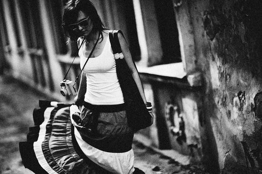 Artistic black and white photo of a woman with a classic camera outdoors.