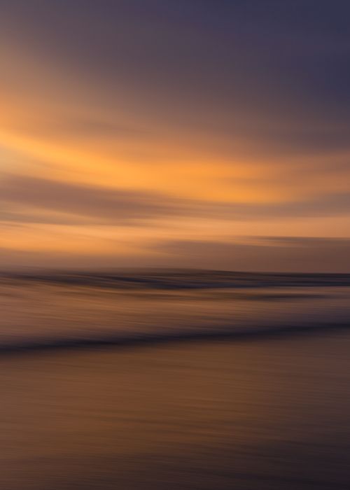 Free Tranquil seascape at sunset with calm waves and vibrant sky colors. Stock Photo