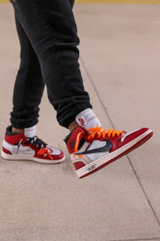 Close-up of red and white Air Jordan sneakers worn by a person on pavement.