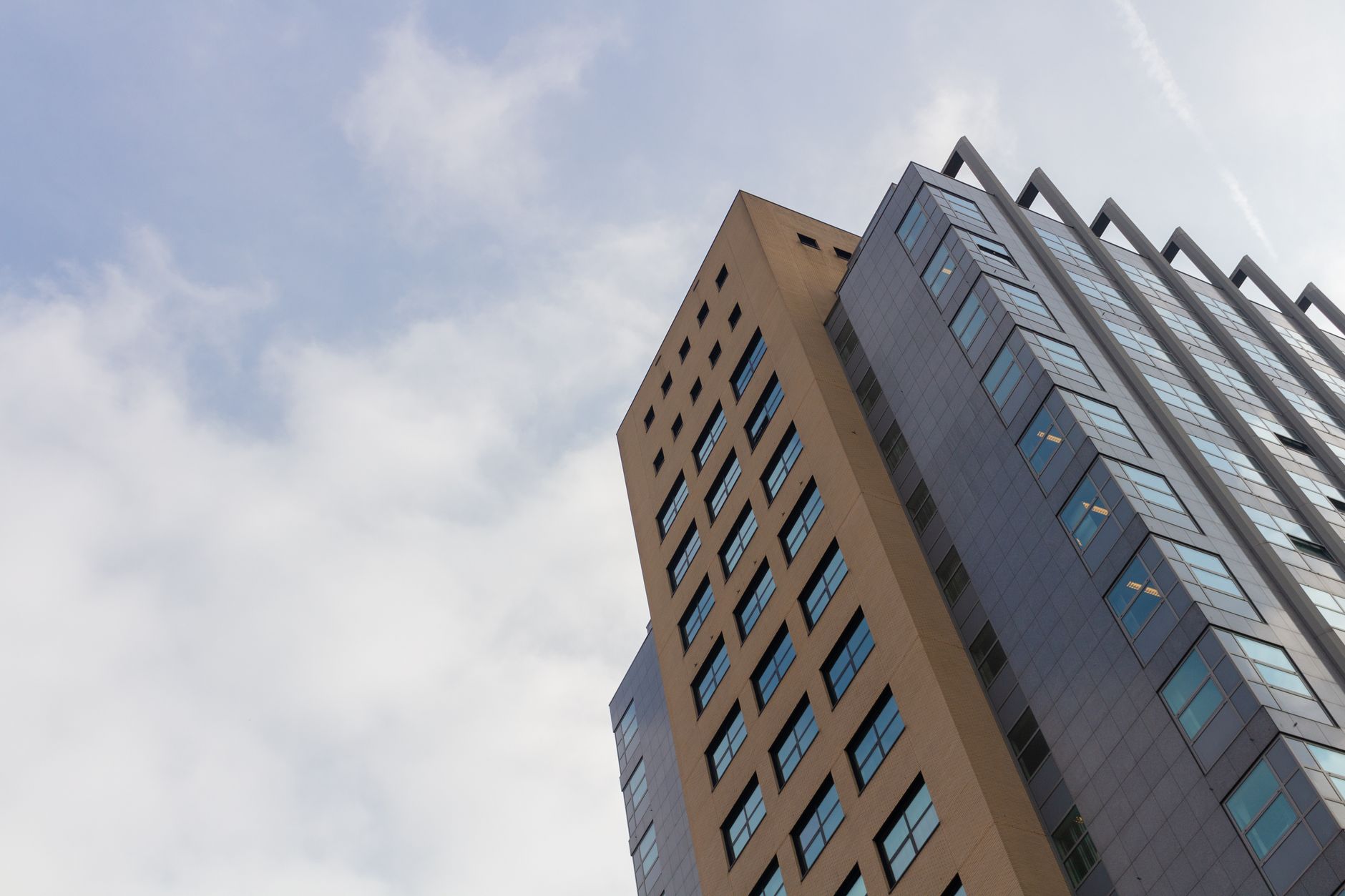 A sleek skyscraper with glass windows in Utrecht, Netherlands, under a cloudy sky.