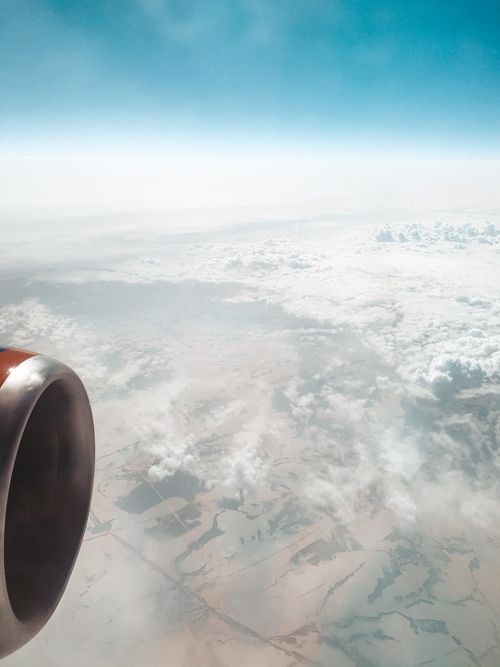Free Captivating aerial view from an airplane wing over clouds and landscape below, showcasing air travel scenery. Stock Photo