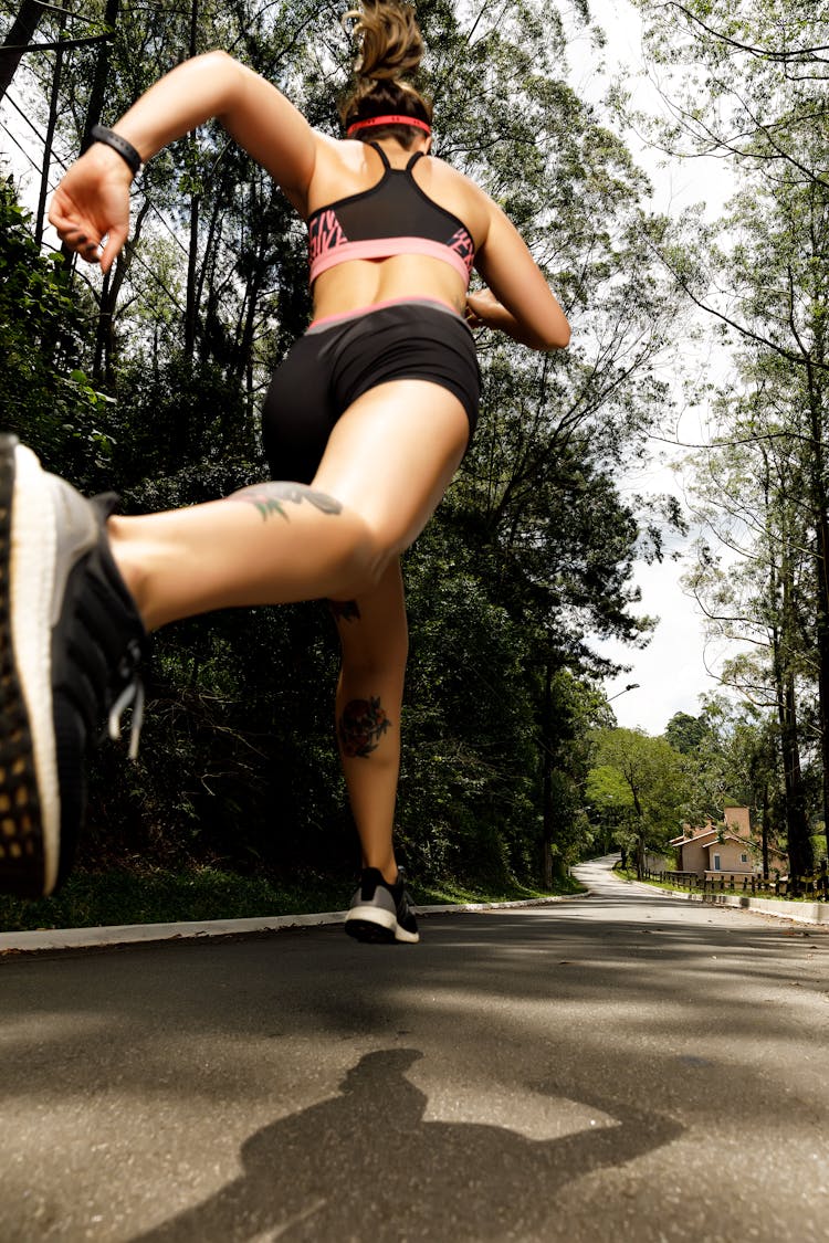 A Low Angle Shot Of A Woman In Black Sports Bra Running On The Street