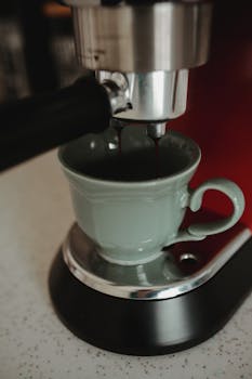 Close-up of espresso flowing into a cup from a coffee maker, highlighting the brewing process.