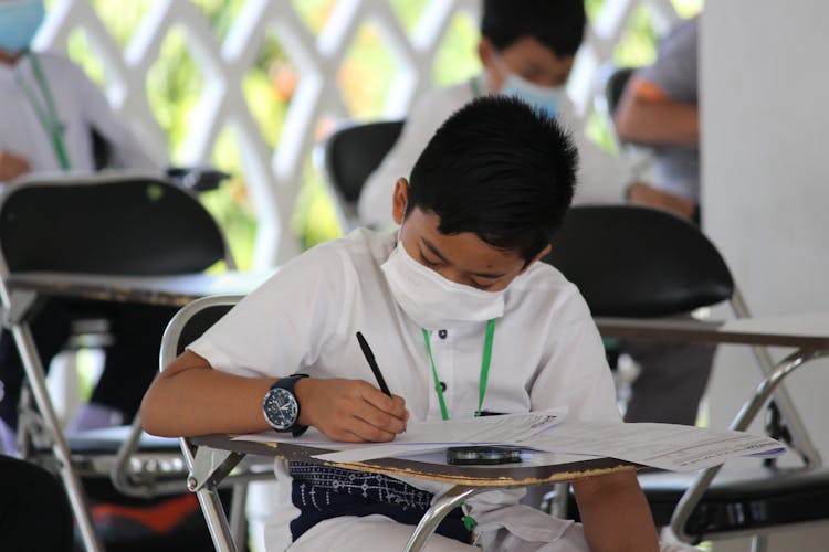 Boy Writing In Notebook In Class