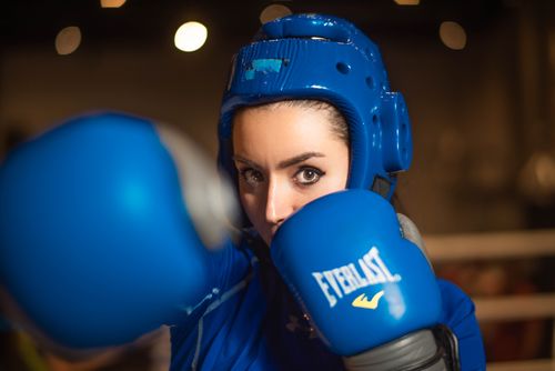 Free A female boxer wearing blue gear preparing to punch inside a gym. Stock Photo