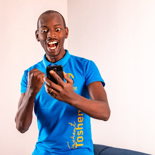 A Man in Blue Polo Shirt Holding His Mobile Phone