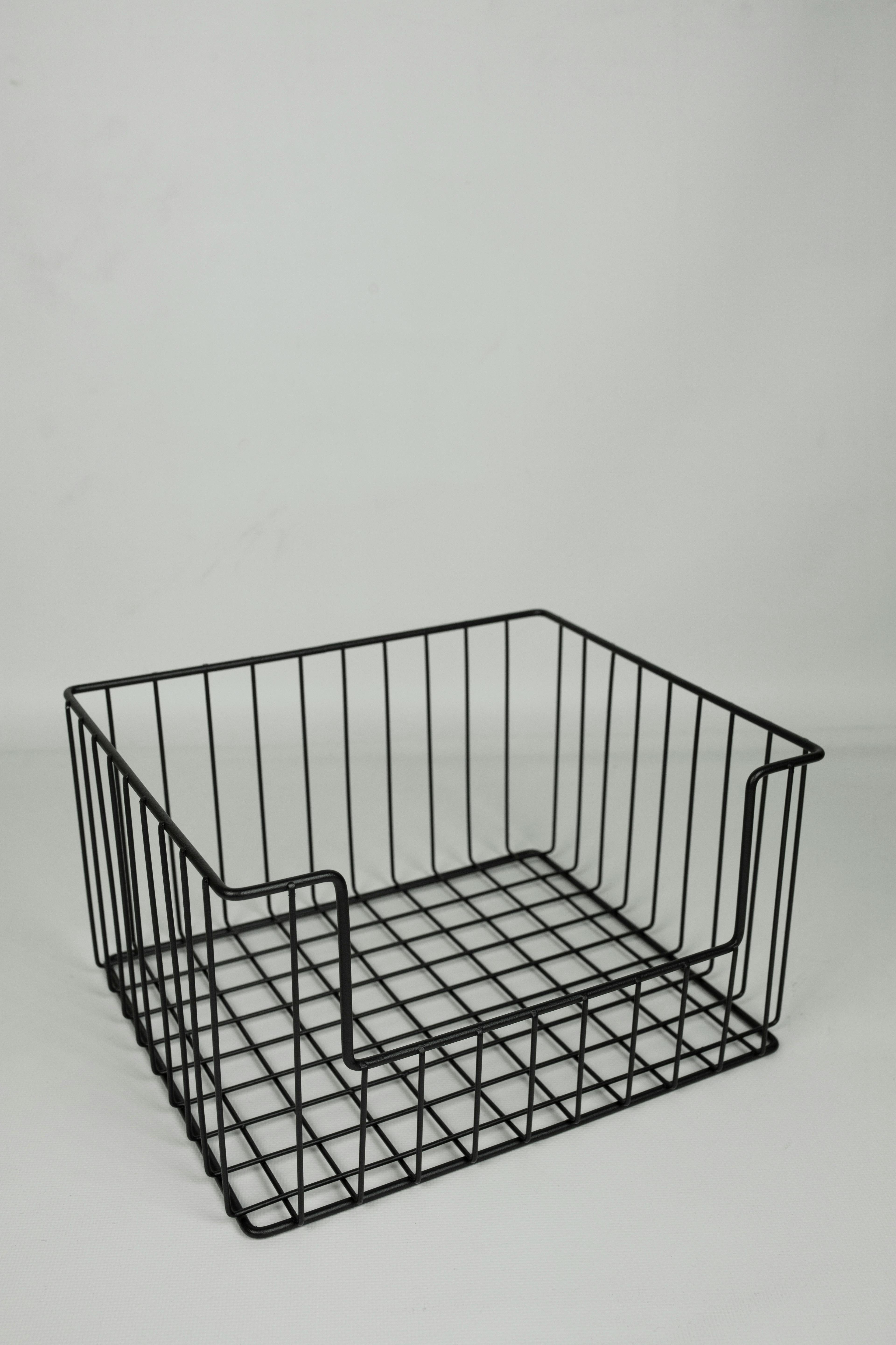 A sleek black metal wire basket captured in a minimalist studio environment.