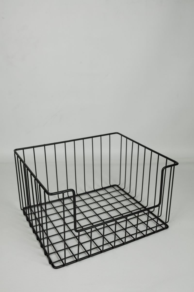 A sleek black metal wire basket captured in a minimalist studio environment