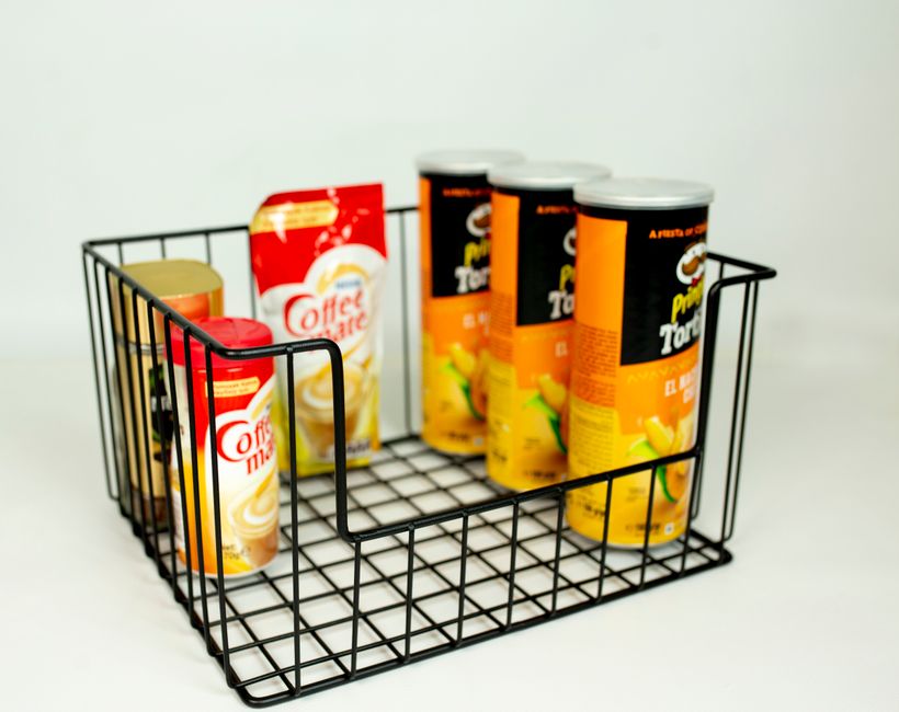 A collection of snack and coffee items in a wire basket on a white background, perfect for pantry organization.