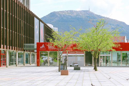 Free Exterior view of Grieghallen in Bergen, Norway, against a mountain backdrop. A tranquil town square scene. Stock Photo