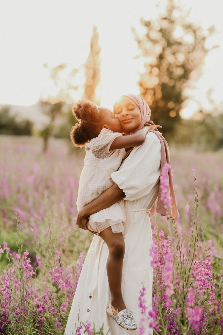 Daughter Kissing Mother In Meadow