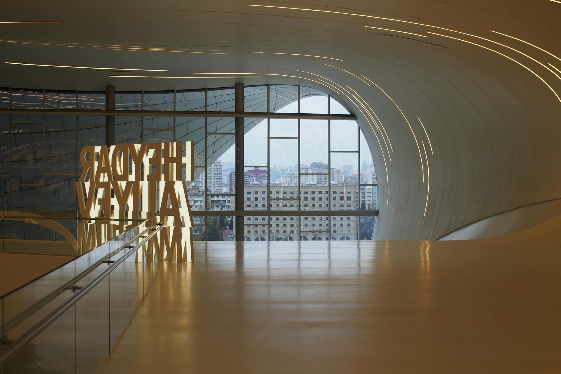 Futuristic interior view of Heydar Aliyev Centre with glass windows showcasing Baku cityscape.