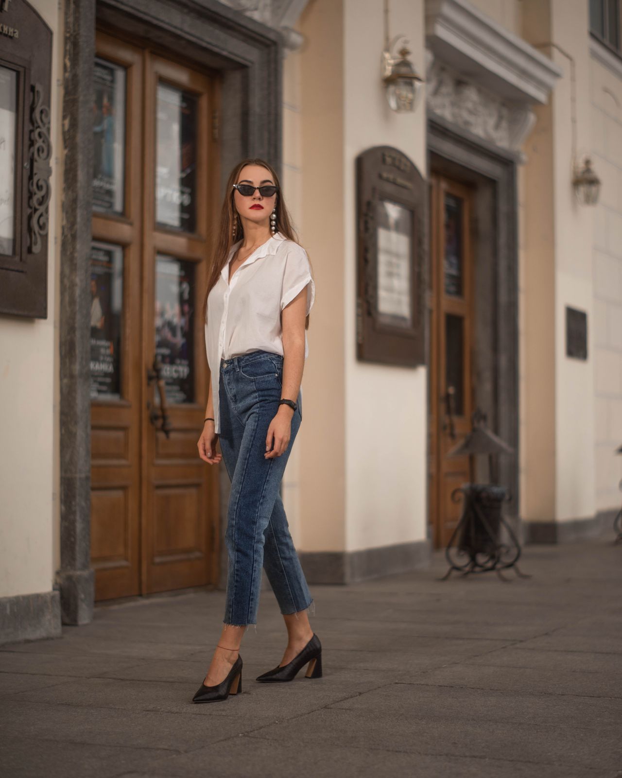 Woman in a white blouse, dark jeans and black block heels