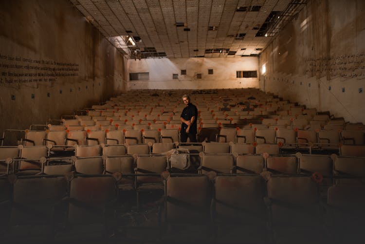 Man Standing In Devastated Movie Theater Audience