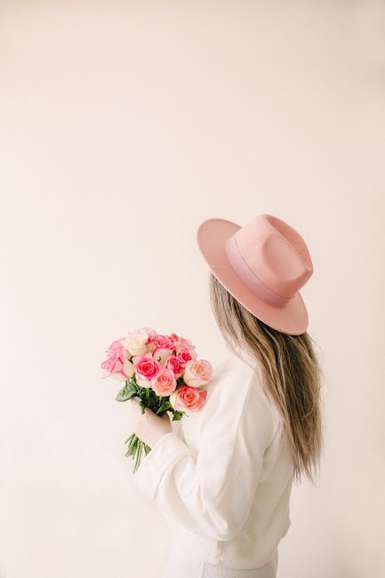 Stylish woman in pink hat holding a bouquet of roses, perfect for spring inspiration and floral themes.