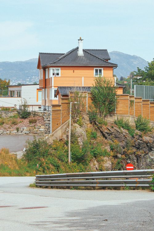Free Orange house in Bergen, Norway, with mountain backdrop and lush greenery. Stock Photo