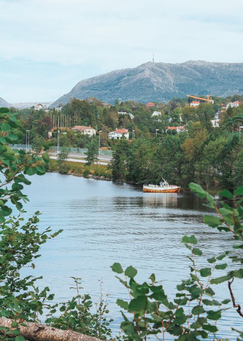 Free A picturesque view of Bergen, Norway, showcasing a tranquil river and surrounding mountains. Stock Photo