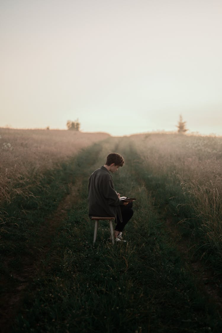 Man Reading Book In Field