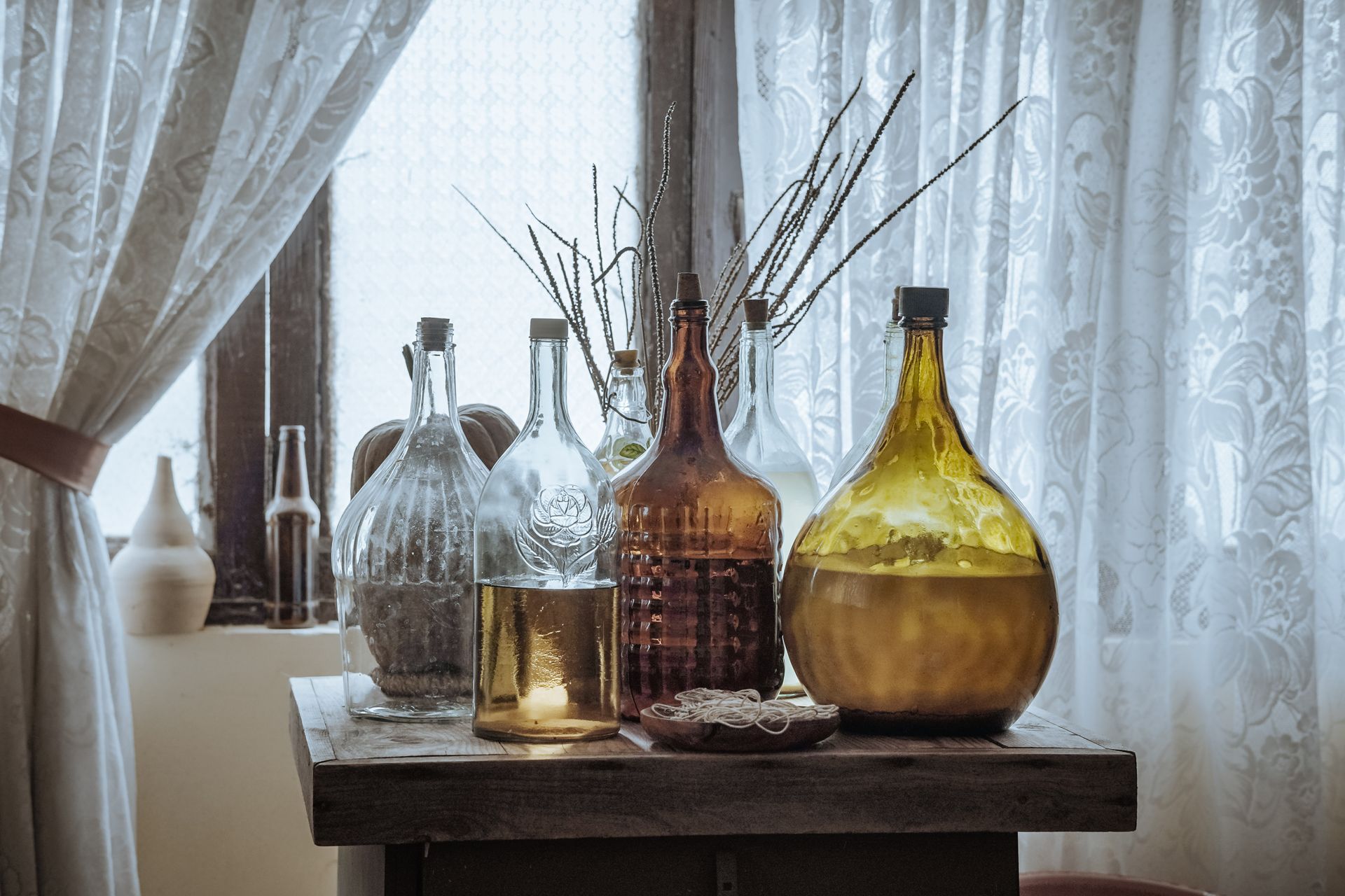 Una vieja botella de vidrio y una cuchara sobre una oscura mesa de madera antigua