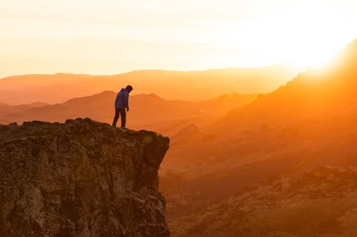 Man Standing on Rocks over Abyss at Sunset