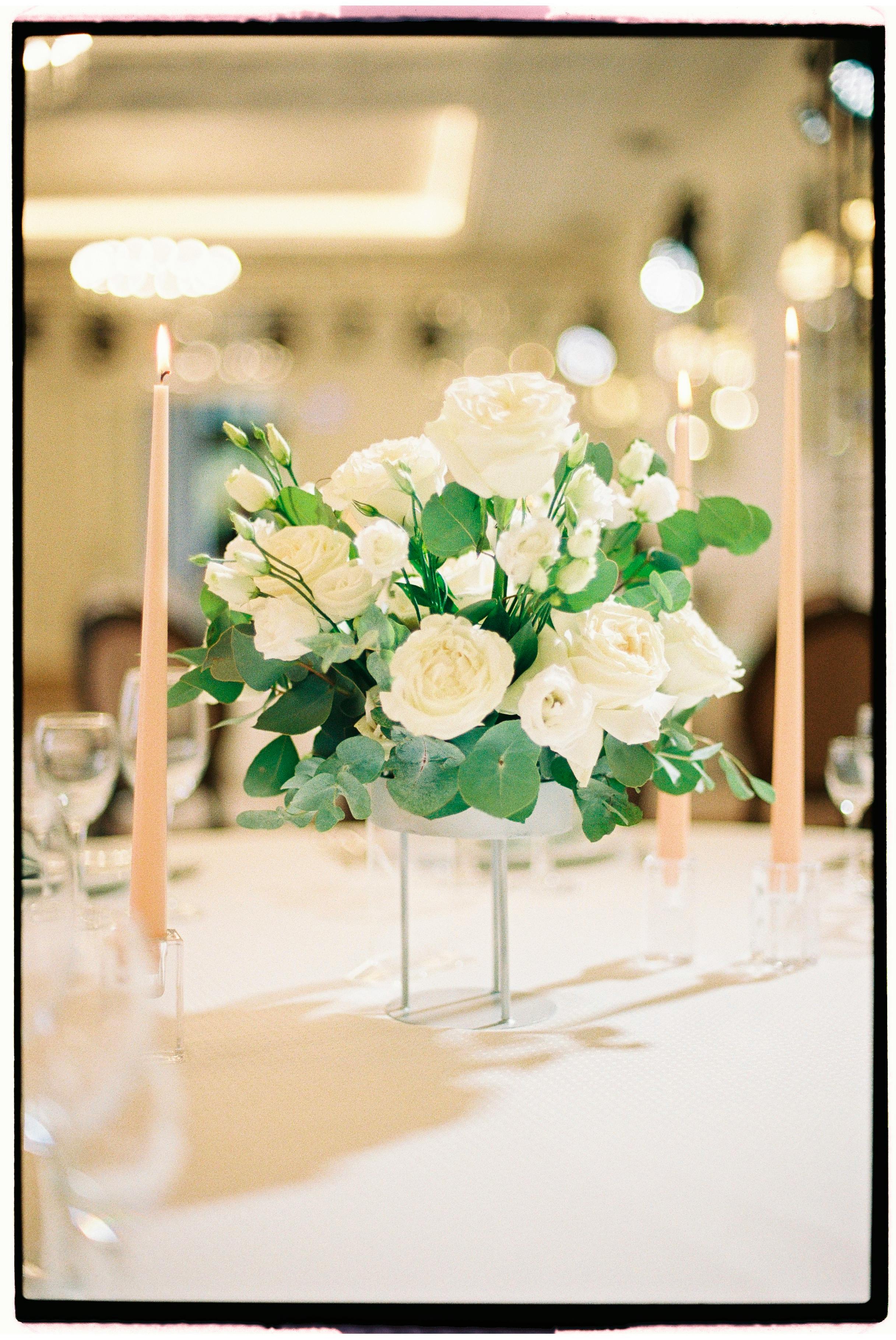Beautiful white rose centerpiece with candles creating a romantic wedding atmosphere.