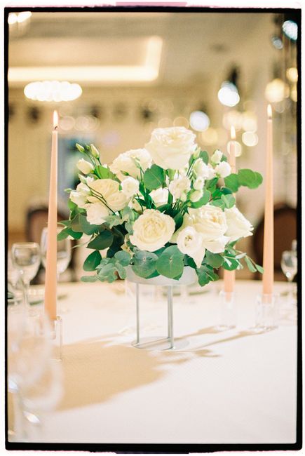 Beautiful white rose centerpiece with candles creating a romantic wedding atmosphere.