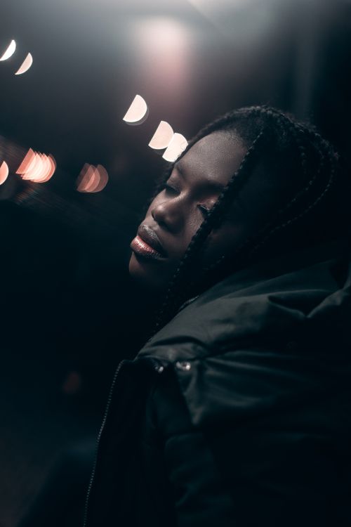 Free Moody portrait of a woman with closed eyes, relishing night lights in an urban setting. Stock Photo
