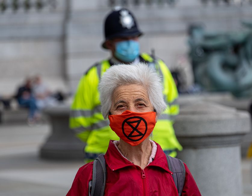 Senior woman protesting with mask for climate change in Trafalgar Square, London during a peaceful demonstration.