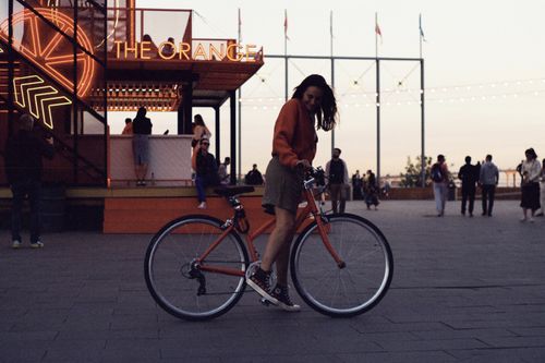 Free Woman with bicycle at night near illuminated cafe in Saint Petersburg, capturing vibrant urban atmosphere. Stock Photo
